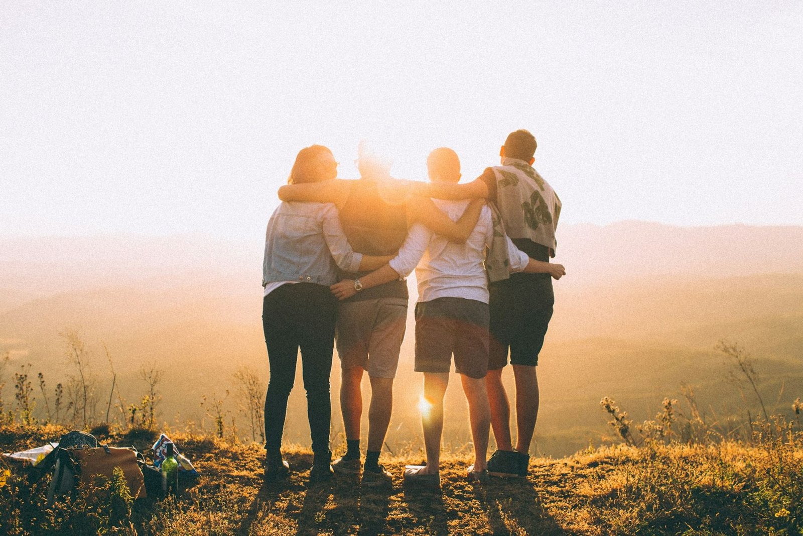Friends with arms around each other watching a sunset